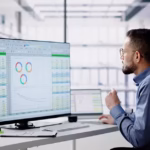 Employee reviewing business data on a desktop monitor in an office